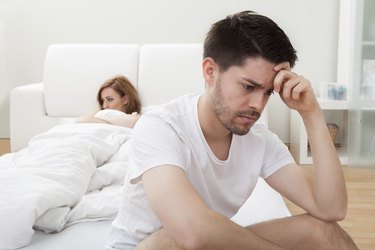 Depressed man sitting on the edge of bed