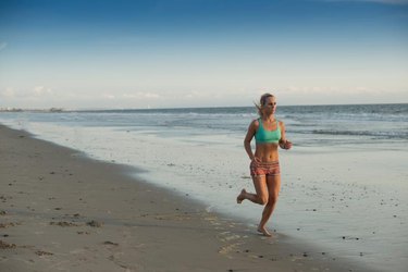 Young woman runs on beach at sunset