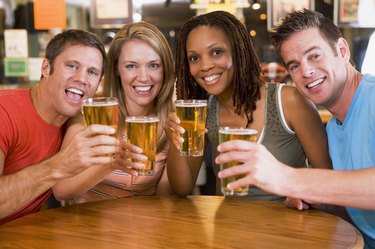 Group of young friends in bar toasting the camera