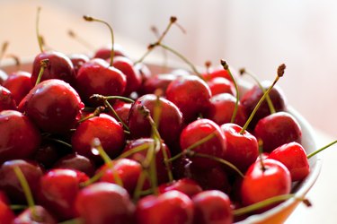 A close view of a bowl full of fresh red cherries with stems
