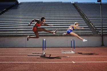women jumping over track hurdles