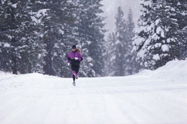 Woman jogging along road in winter