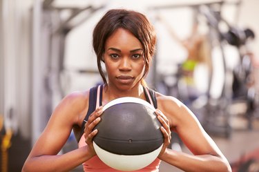 Portrait of a woman holding a medicine ball at gym