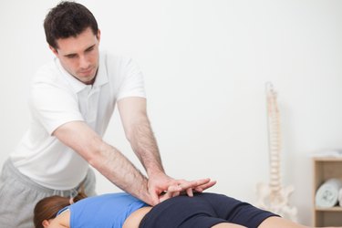 Practitioner pressing the lower back of woman while standing in front of her