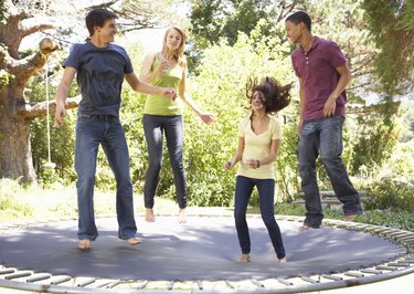 Four Teenage Friends Jumping On Trampoline In Garden