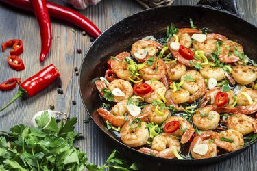 Freshly fried shrimps with herbs on old pan