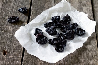 Dried plums on a dark background in a rustic style.