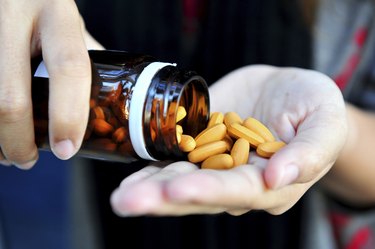 Mature woman with pills or vitamins on her hand