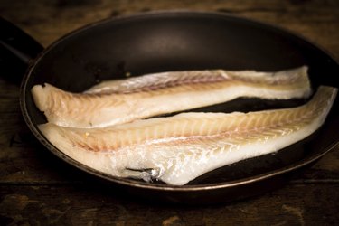 Two haddock fillets in frying pan