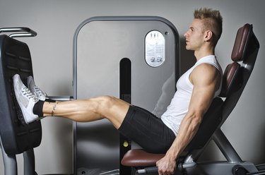 Attractive and fit young man in gym working out legs