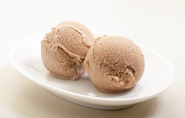 three flavored ice cream scoops on a pale blue plate, with