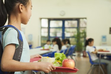 女生在学校食堂举行食品托盘