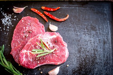 Fresh beef steaks with ingredients on the dark background