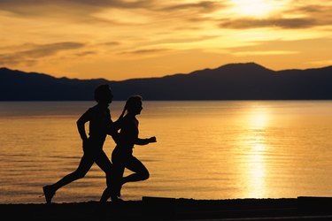 Silhouette of couple jogging on beach
