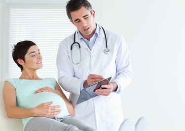 Pregnant woman lying down talking to her doctor