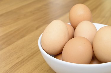 Eggs in white bowl on wooden table