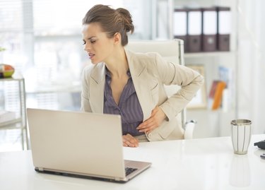 business woman with stomach ache in office