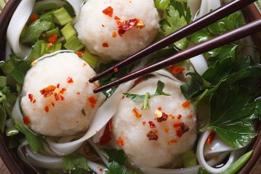 Asian soup with fish balls and chopsticks macro top view