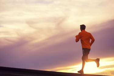 Male runner silhouette, running into sunset