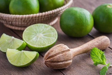 Wooden squeezer and lime on table