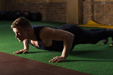 Athletic man doing push ups in gym