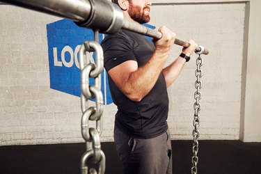 man lifting a barbell with chains