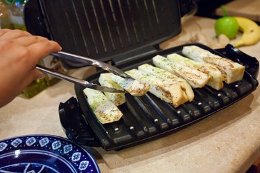 Person using indoor electric griddle to grill white eggplant