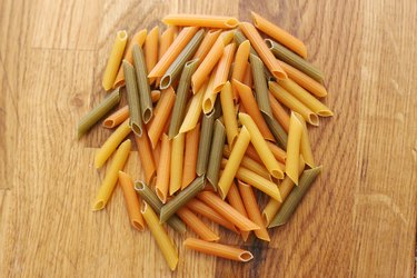 top view of dry tricolor penne pasta on a wooden table