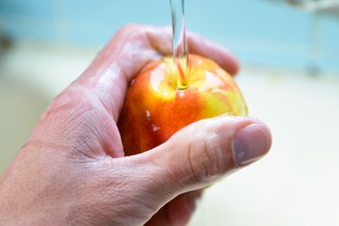 hand washing whole peach under running water