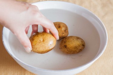 washing potatoes in a bowl of water