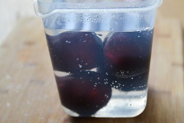 whole plums in plastic container with clear syrup