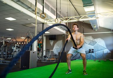 man doing battle ropes in the gym