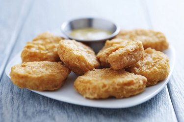 chicken nuggets on white plate with mustard dipping sauce in small stainless steel bowl