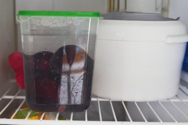 whole plums in plastic container in freezer