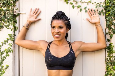 woman doing standing wall slide shoulder stretch outside