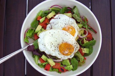 Eggs on top of a bowl of salad