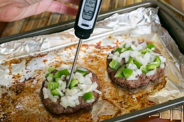 close up of meat thermometer reading 161 degrees Fahrenheit in hamburger patty in the oven