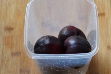 whole plums in plastic container