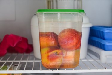whole peaches in plastic container in freezer