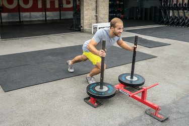 Men demonstrating sled push exercise as part of a HIIT workout for calorie burn