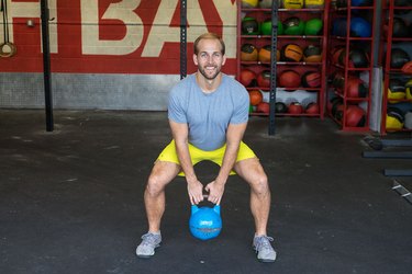 Man demonstrates sumo kettlebell squat exercise for a HIIT workout to burn calories