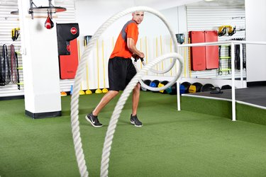Man using the battle ropes during a workout at his gym