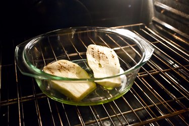 Large glass baking dish with olive oil and white eggplant in  the oven