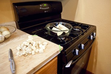 picture of white eggplant in a baking dish on top of the stove next to pieces of chopped white eggplant on a cutting board