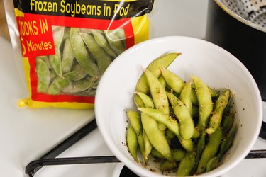 Steamed frozen edamame in a white serving bowl.