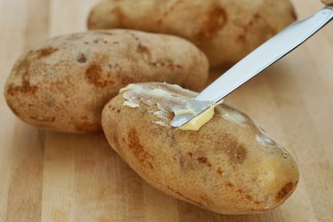 spreading butter on potato