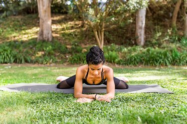 woman doing frog stretch on a yoga mat outside