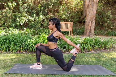 woman doing kneeling quad stretch on yoga mat outside