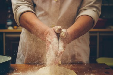 A baker claps some flour from his hands.