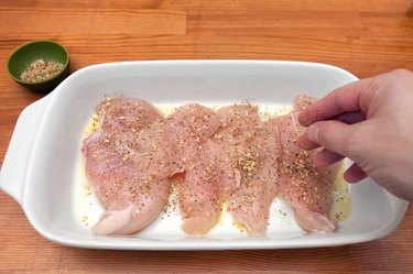 Seasoning chicken breasts in a baking dish